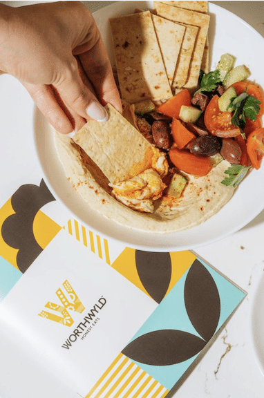 Close-up of Mediterranean shareable plate with pita, hummus, and olives at Worthwyld Happy Hour
